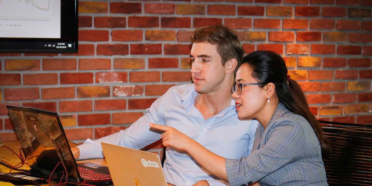 Here’s How to Use Data to Transform Your Creative Operations Two people sitting at a computer pointing at the screen.